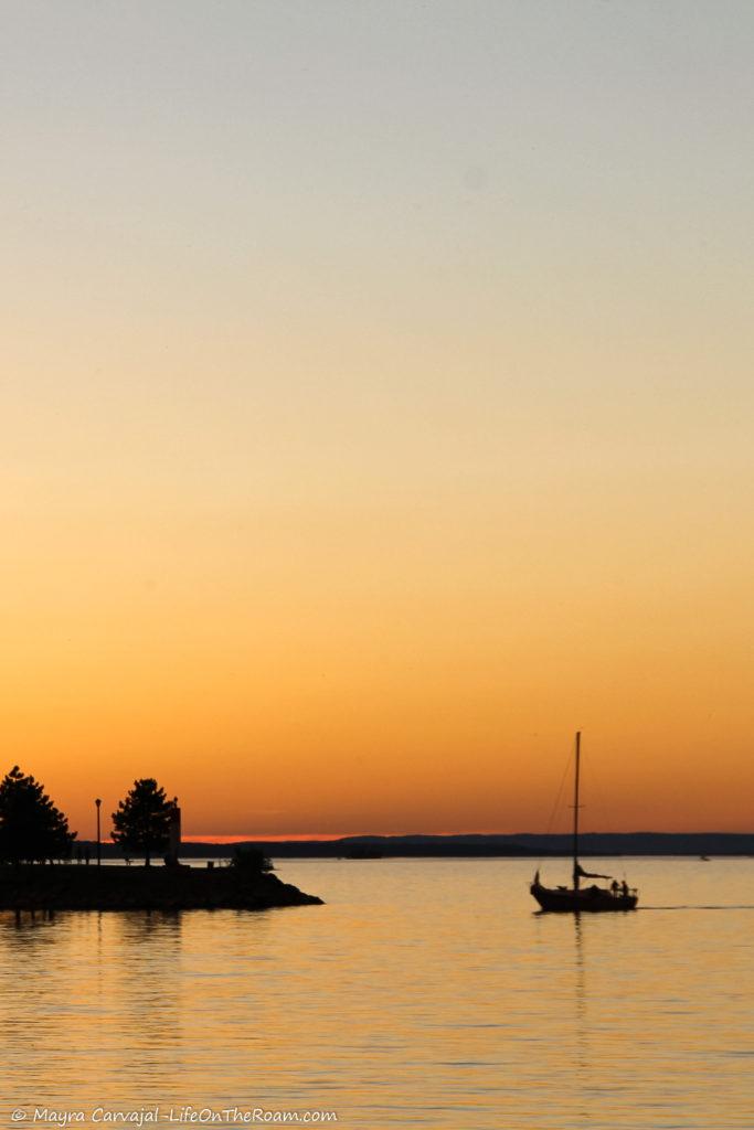 View of a sunset over the water and a boat in the distance