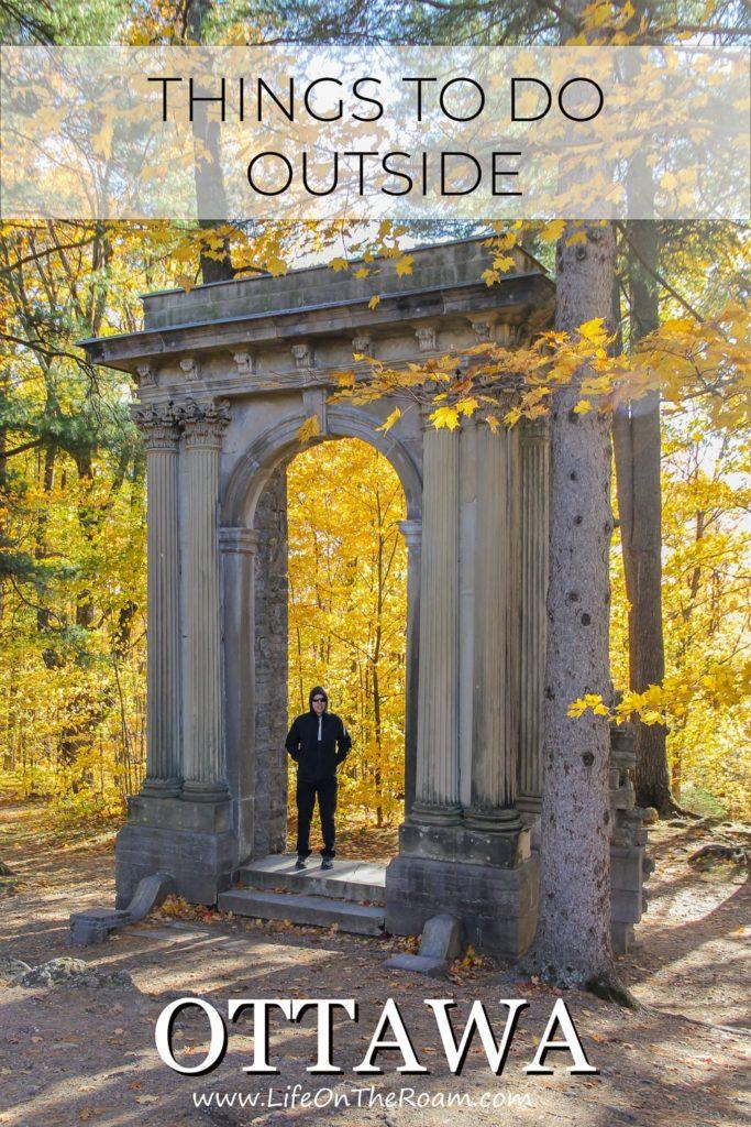 A man standing under an arch in a forest