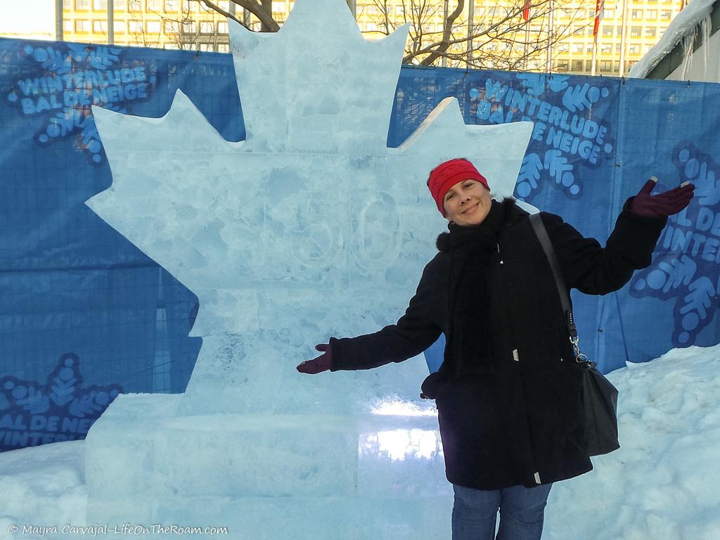 A woman posing with an ice sculpture in the shape of a maple leaf