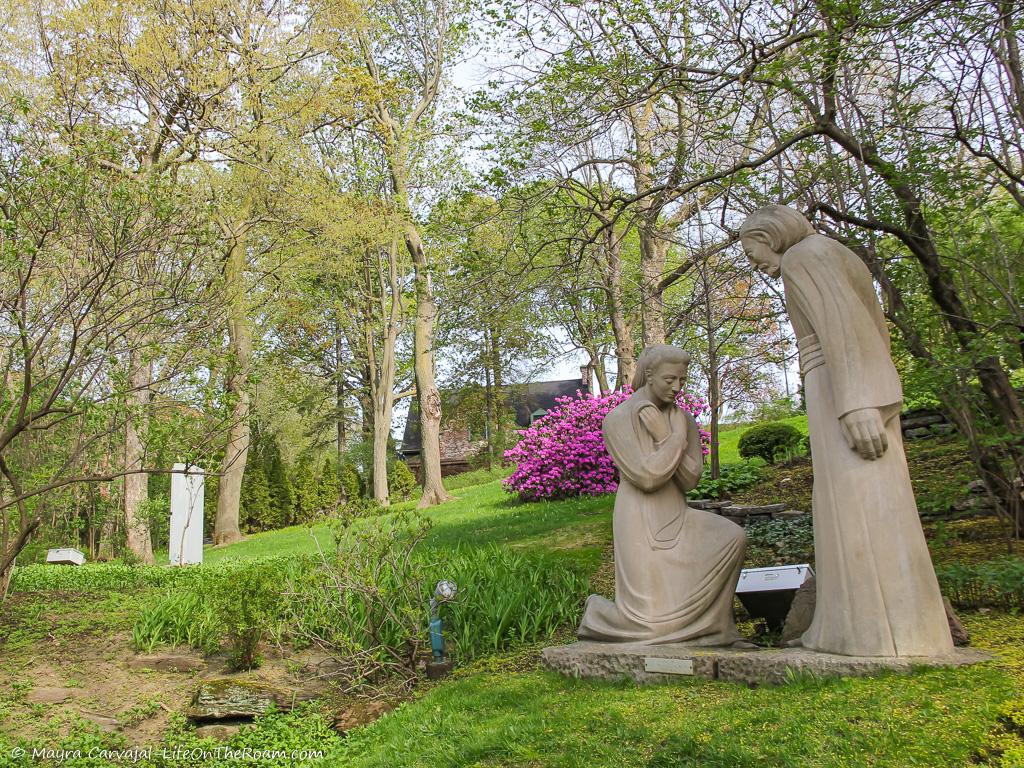 Outdoor sculptures in a garden setting with trees and flowers in bloom