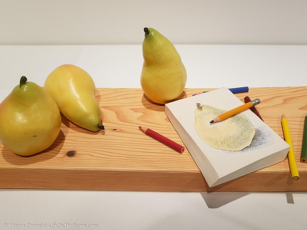 A piece of contemporary ceramic portraying pears on a wood board