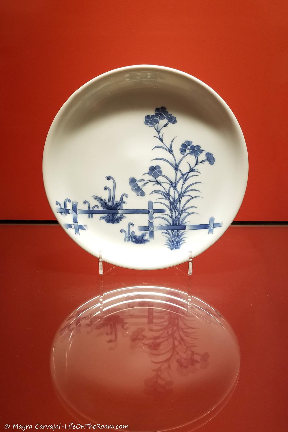 A dish in white porcelain with delicate drawings in blue