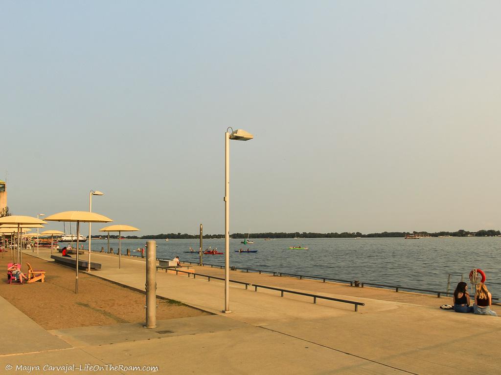 Umbrellas on a man-made beach on a boardwalk along a lake