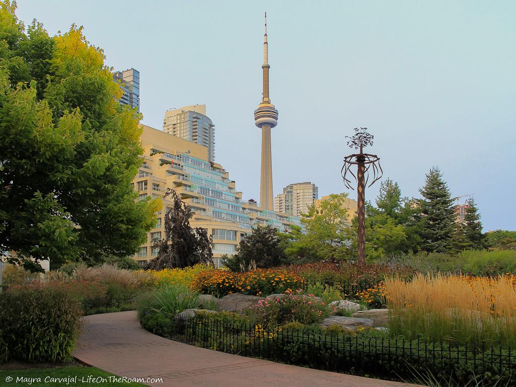 An undulating path in a garden with buildings on the background