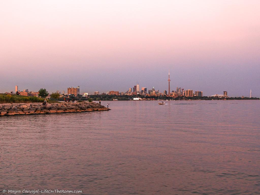 View of a sunset over the water with a city skyline in the background