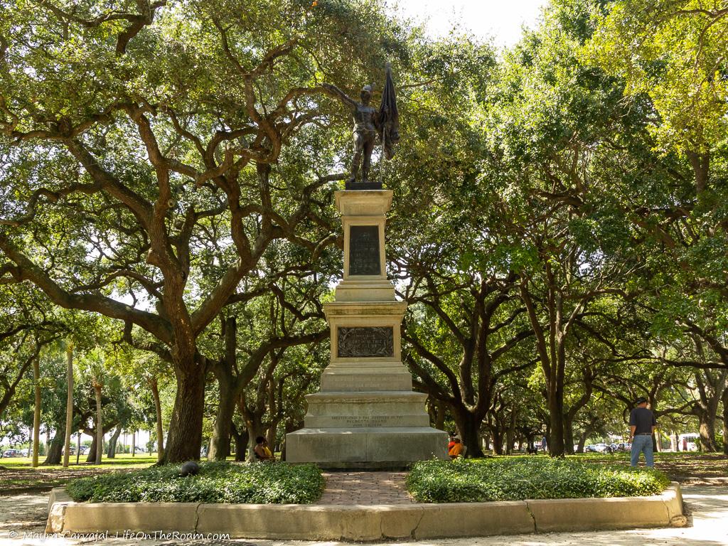 A statue in an urban park with live oaks