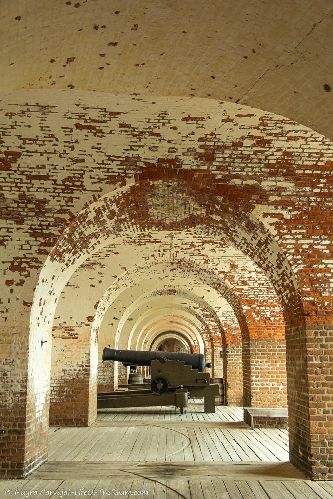 A cannon in the distance in vaulted-ceiling rooms