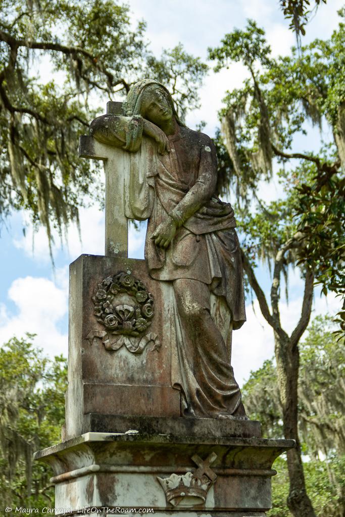 A statue leaning on a cross in a grave