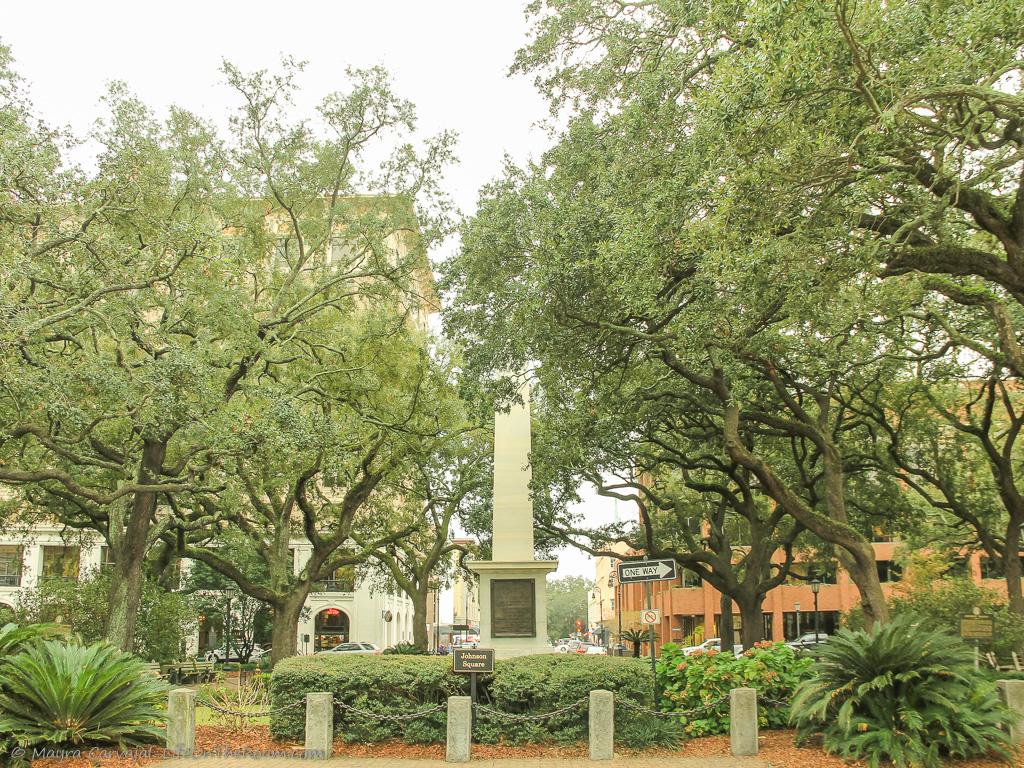 A city square with a monument and mature trees