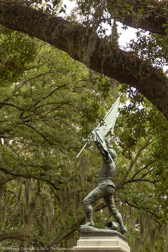 A bronze statue of a Sergeant in a public square with trees