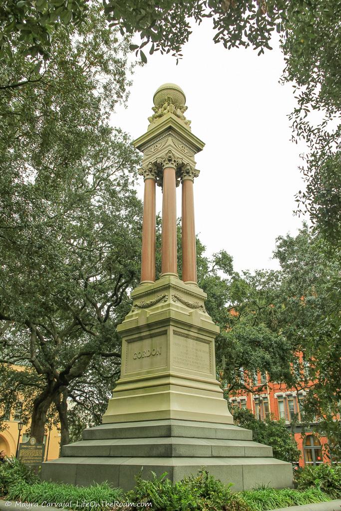 A monument with four columns in a square with trees