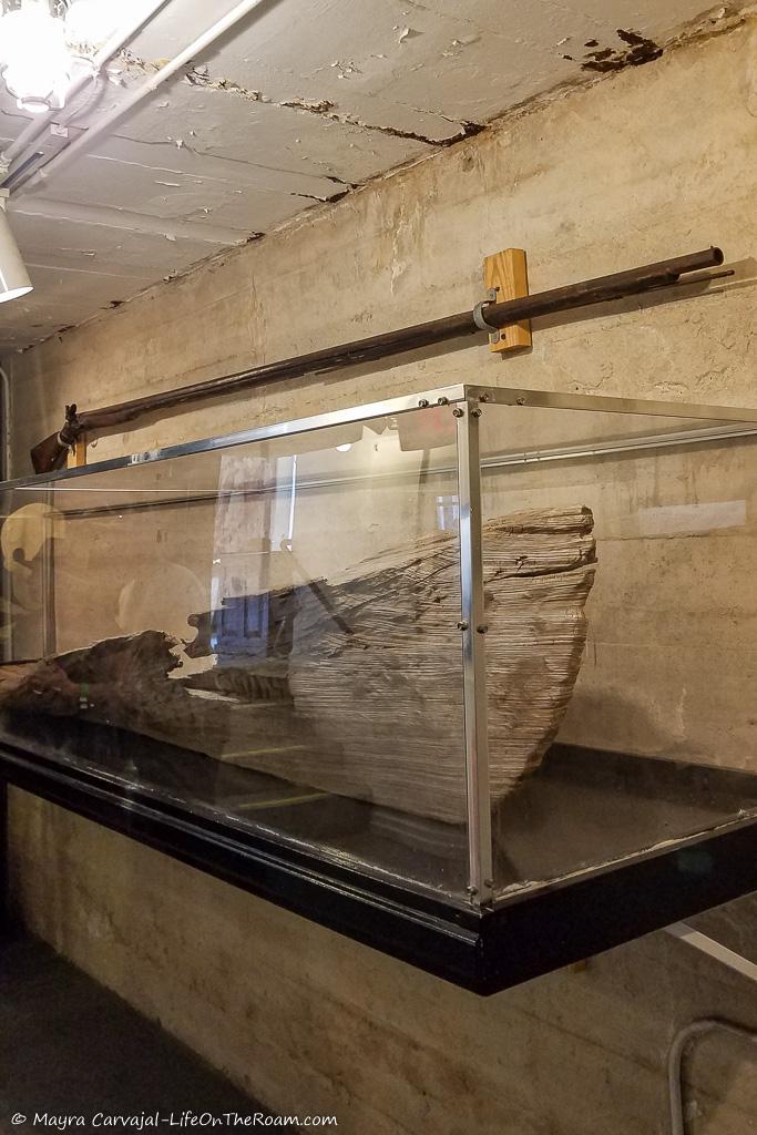 A glass case with an antique boat