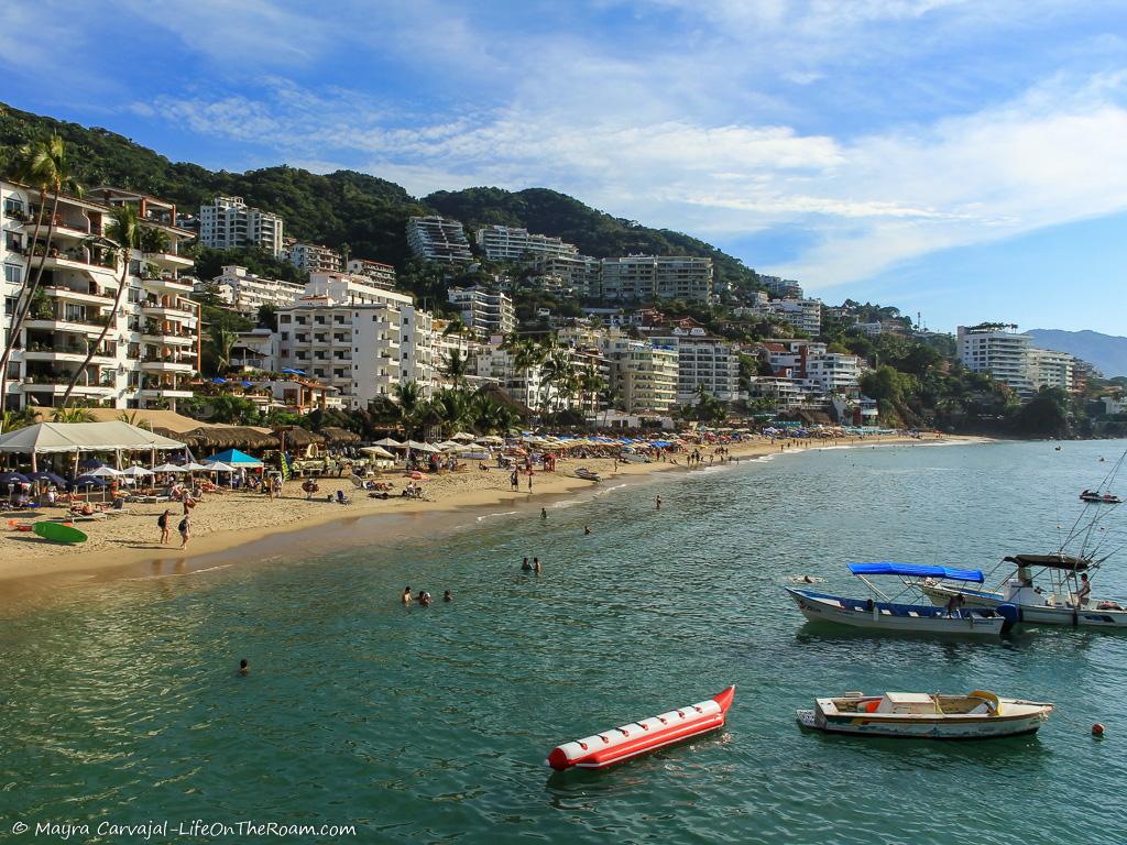 A sandy beach with buildings and mountains in the background