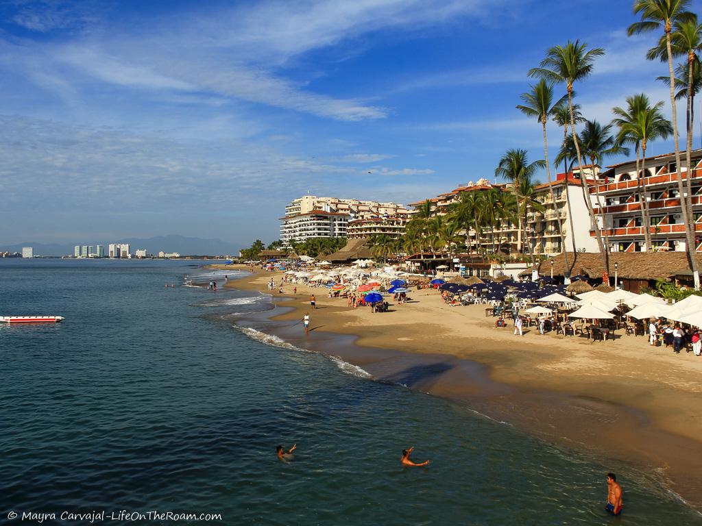 A busy beach with low-rise buildings