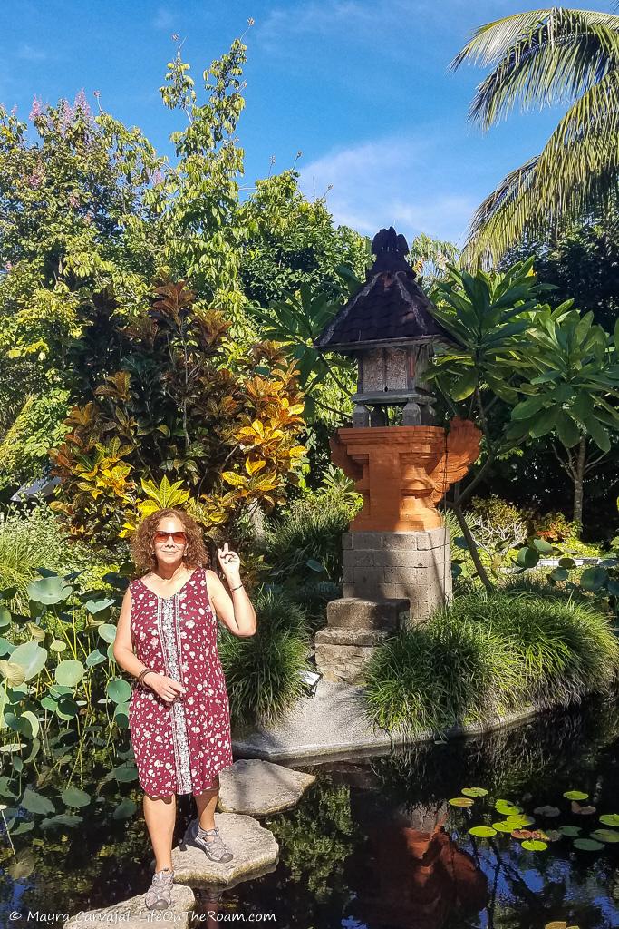 Mayra pointing at a shrine in a small pond