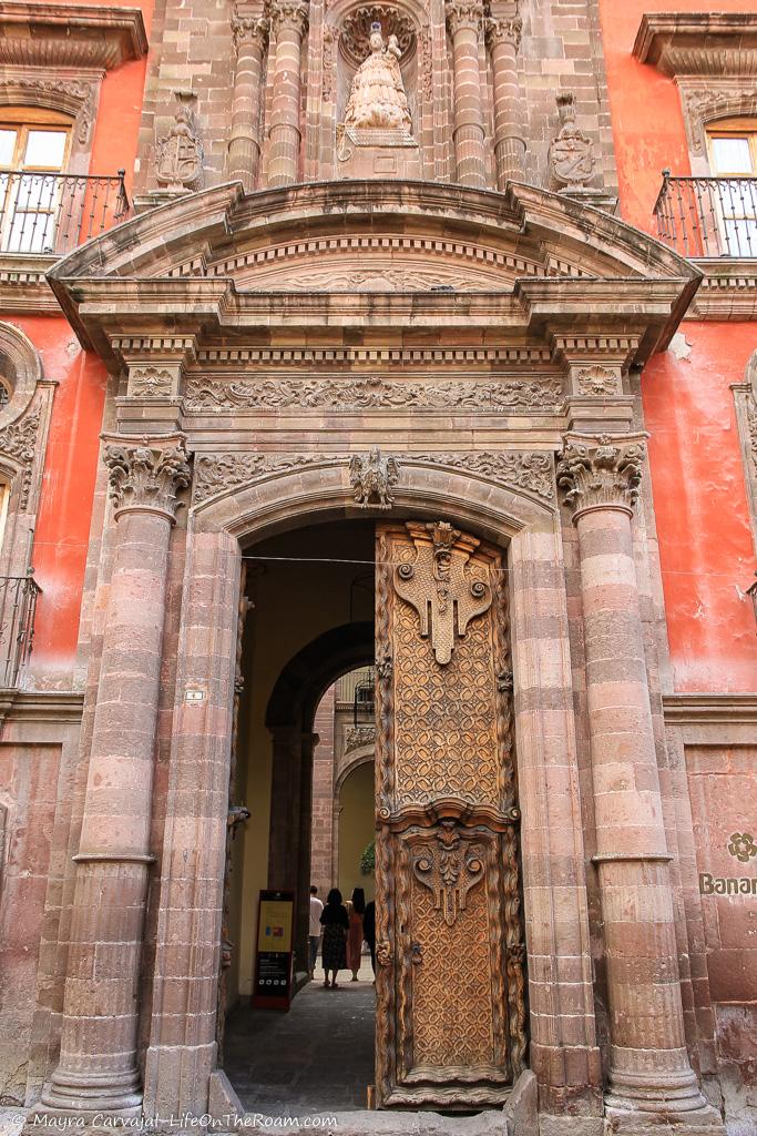 A building with a stone facade and wood doors and intricate carvings