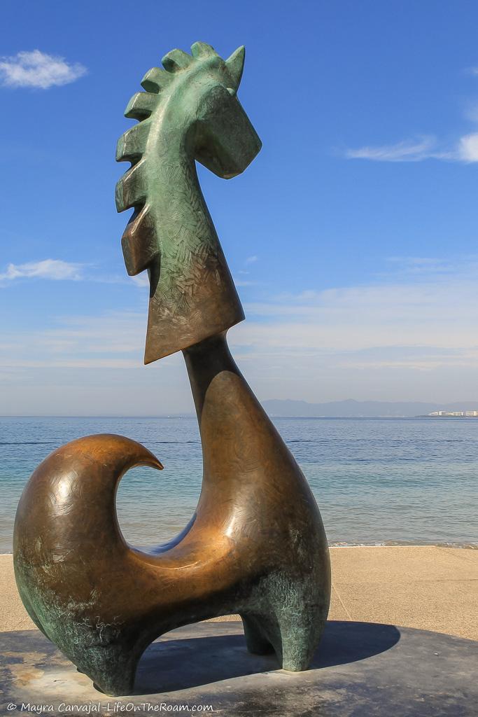 A bronze sculpture of a fantastic figure on a seaside boardwalk