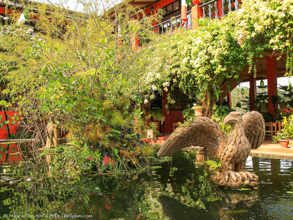 A fountain with sculptures surrounded by plants and flowers, in a garden