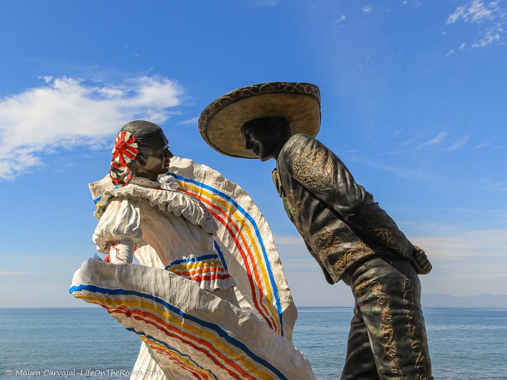 The bronze sculptures of two dancers with the sea in the background