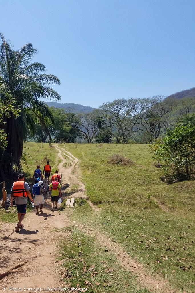 People wearing life jackets walking in an open field with mountains in the background