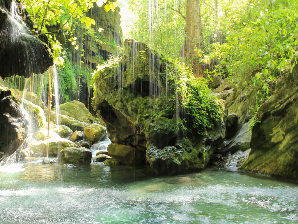 A curtain of water falling from rocks in a creek 