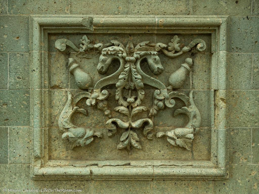 A stone wall plaque with swirl motifs