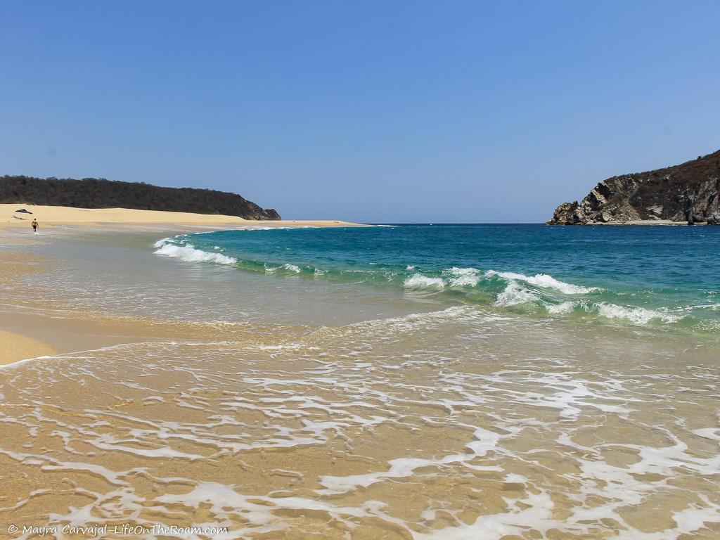 A sandy beach with hills in the background