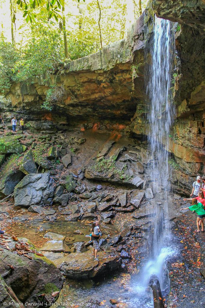 People walking behind a bridal veil fall