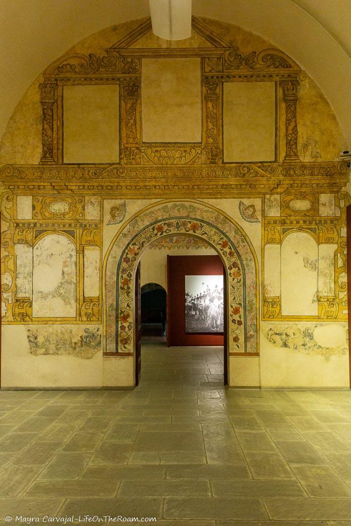 A wall with hand-painted decoration and an arched door