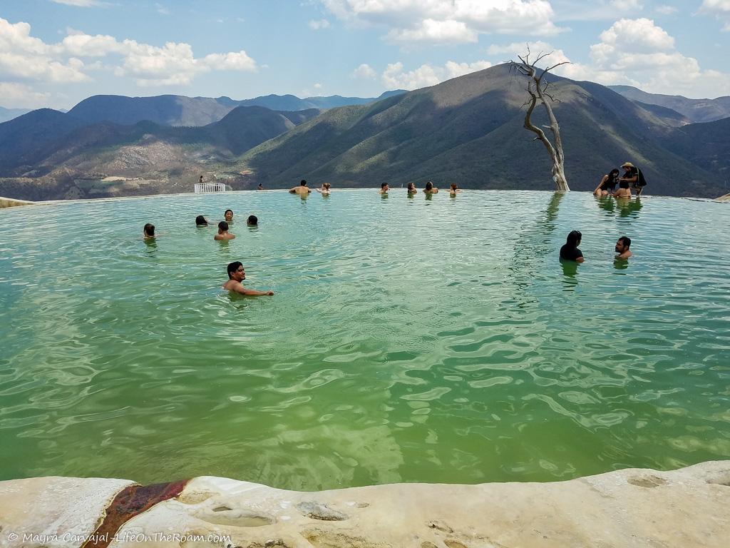 People bathing in a natural pool with a mountain view