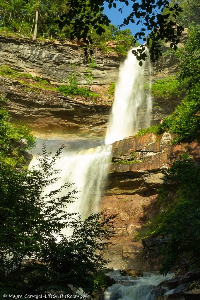 A double cascading waterfall seen through foliage