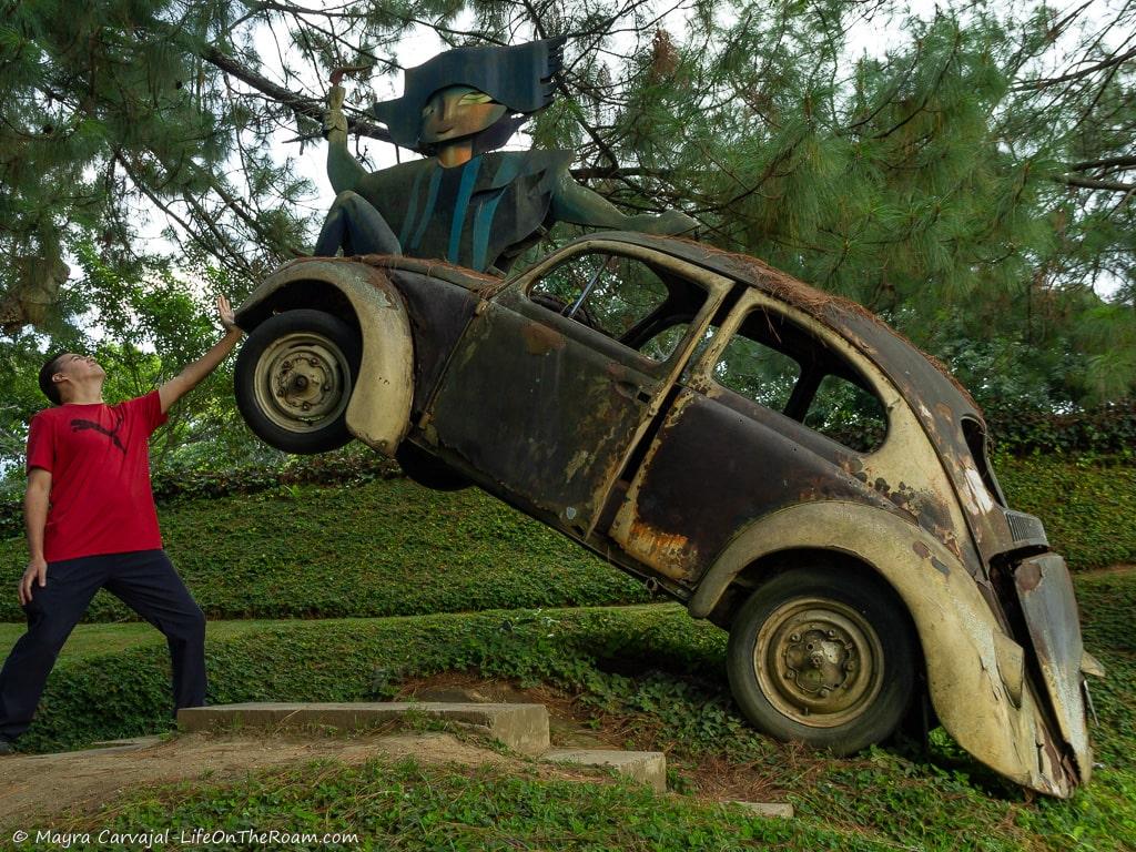 A man pretending to lift a sculpture car