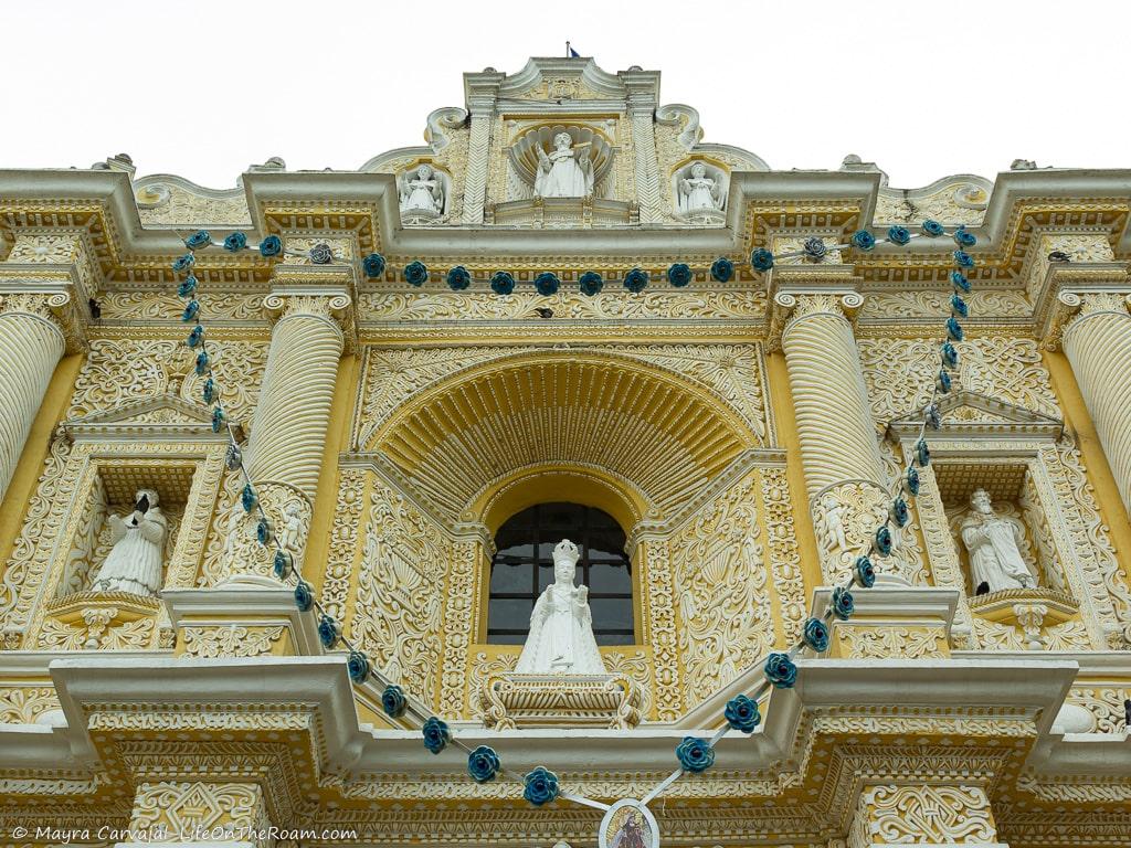 The upper section of a church painted in yellow with ornamentation in white
