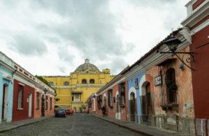 A cobblestone street with colonial-style houses painted in bright colours