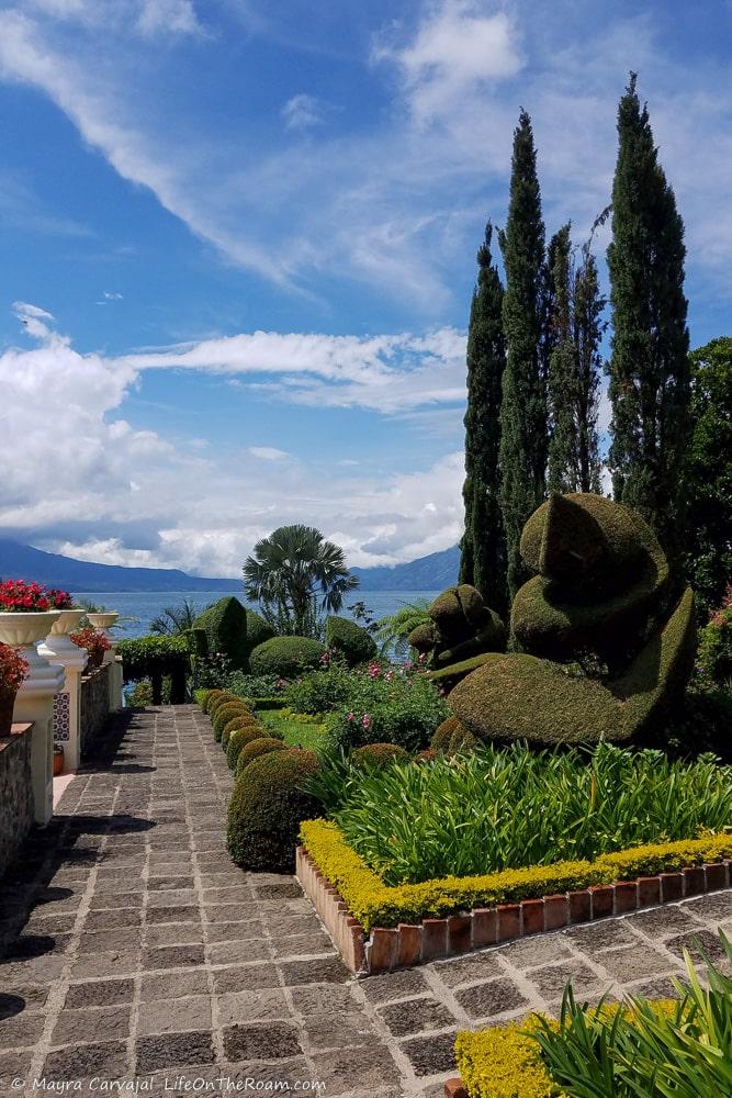 Topiaries in a garden with a lake and volcanoes in the background