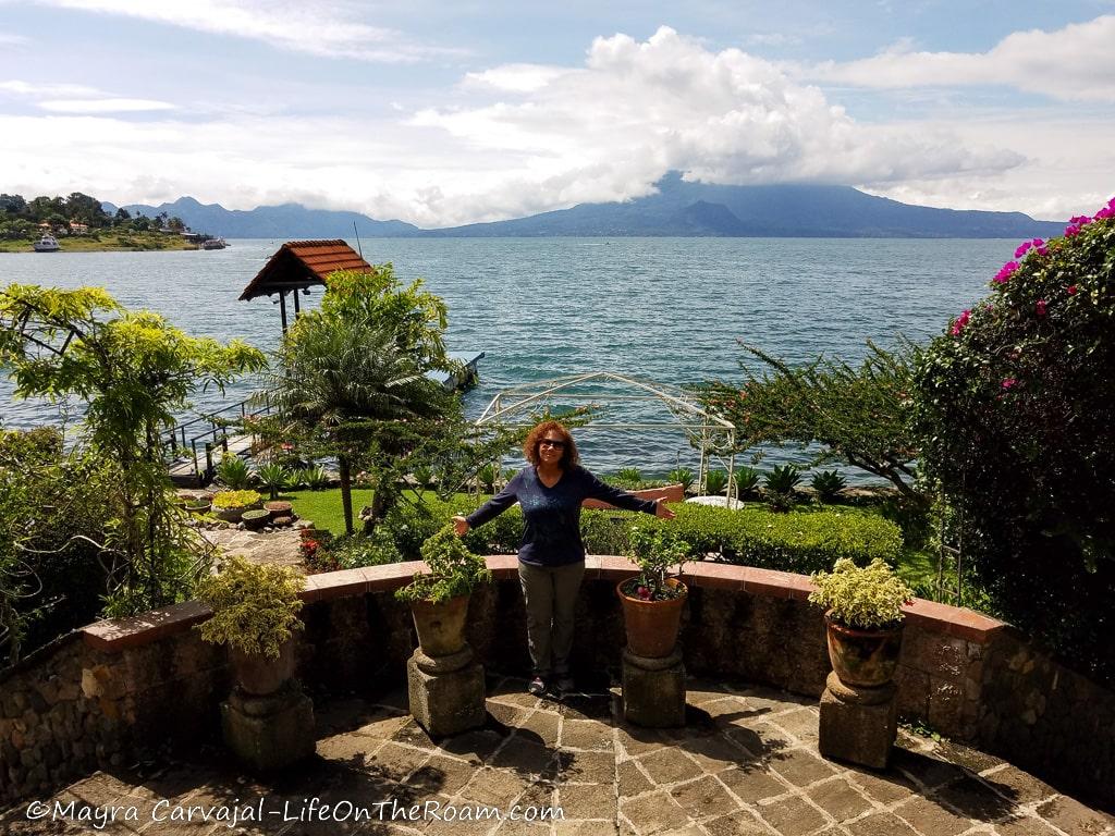 Woman standing on a terrace with a lake and a volcano in the background