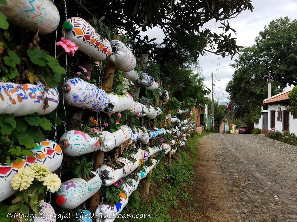 A cobblestone street with painted bottles as planters