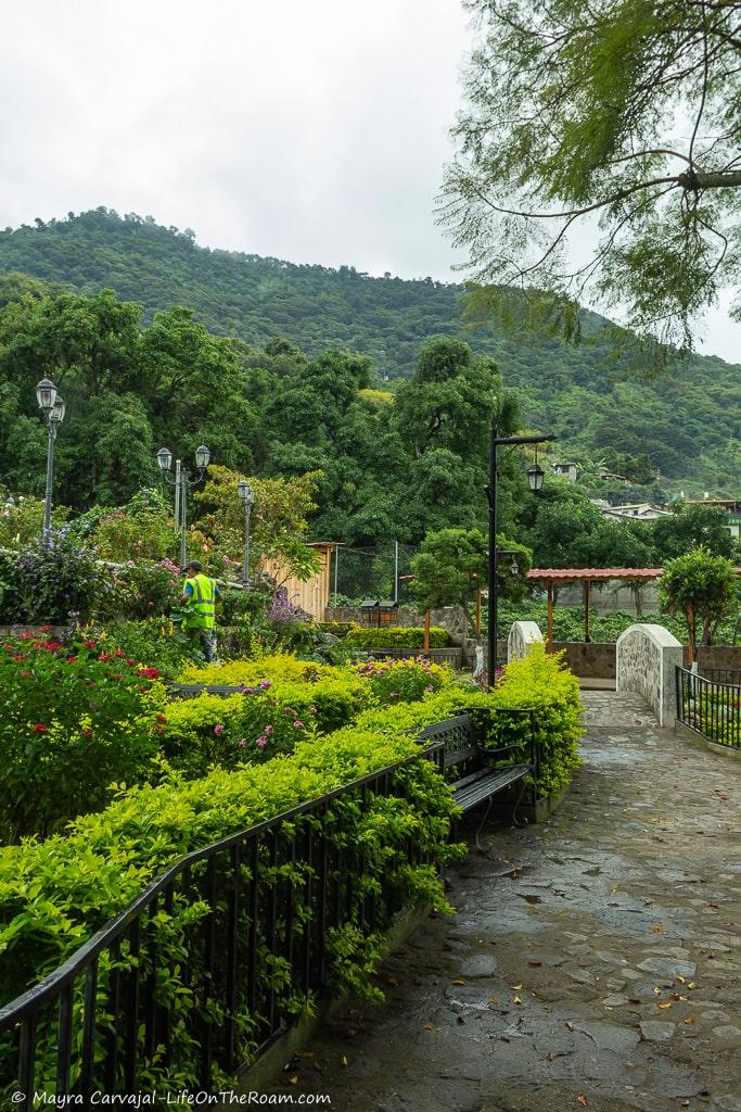 A square with gardens, a bench a bridge, and the mountains in the background
