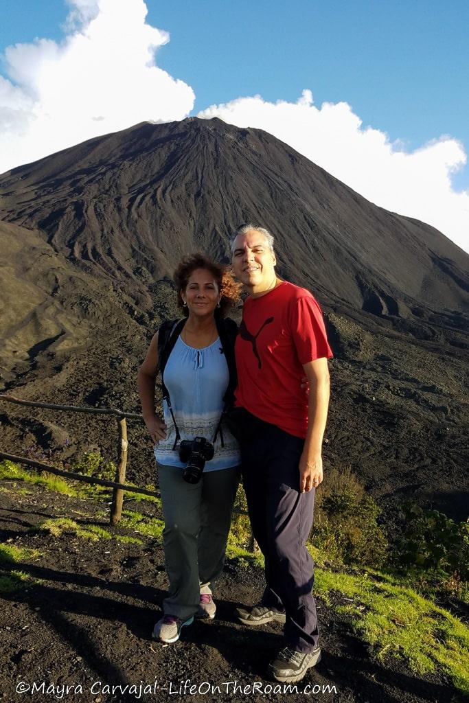 A man and woman standing with a volcano in the background