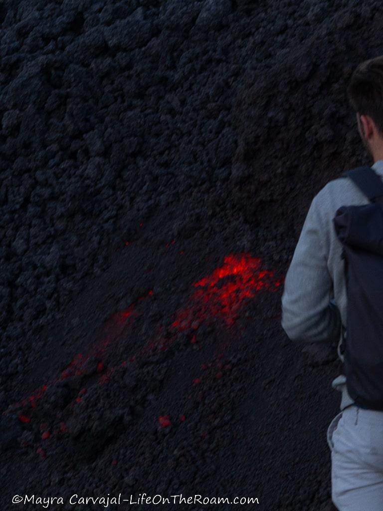 A man looking at hot lava under volcanic rock