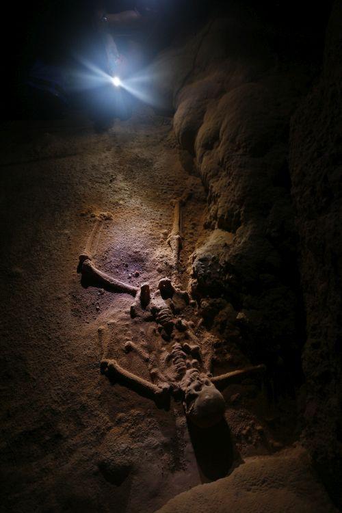 A skeleton covered by calcite, inside a cave