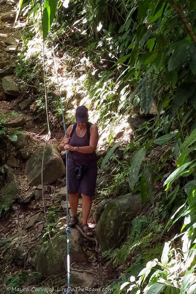 A woman hanging on to a rope on a trail