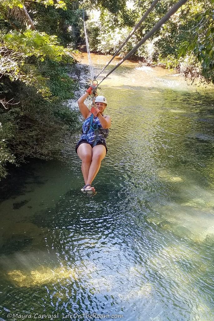 A woman doing ziplining over a river