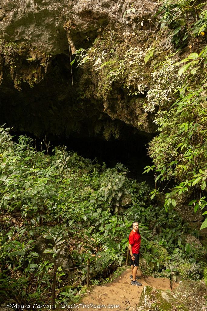 A man standing at the entrance of a cave