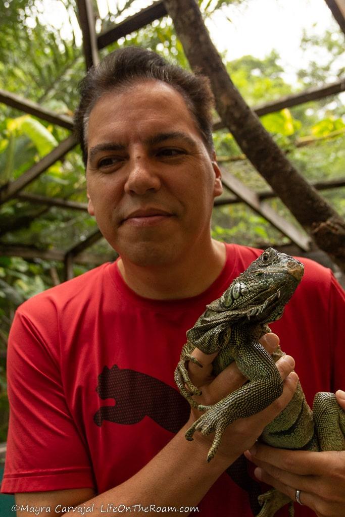 A man holding an iguana