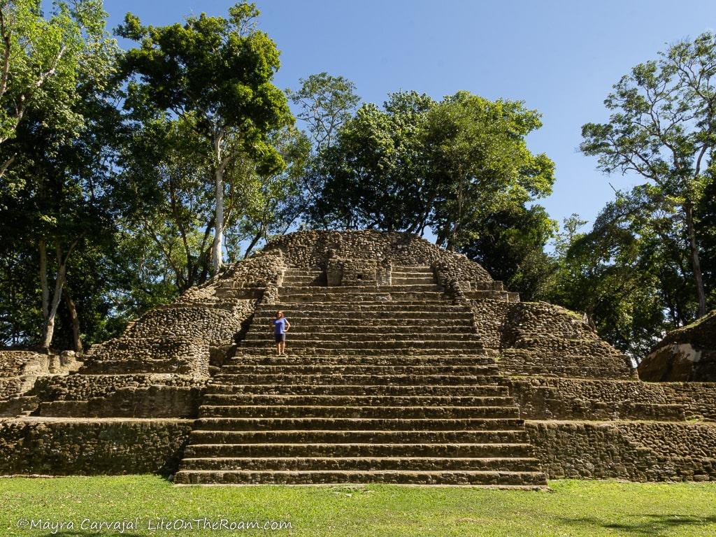 A tall pyramid with central stairs with a woman standing at mid-height