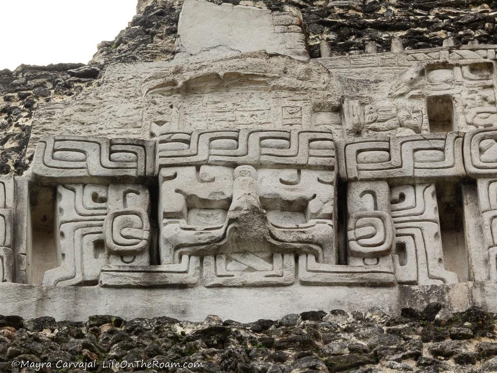 A stucco anthropomorphic mask on a temple with an X under the jaw