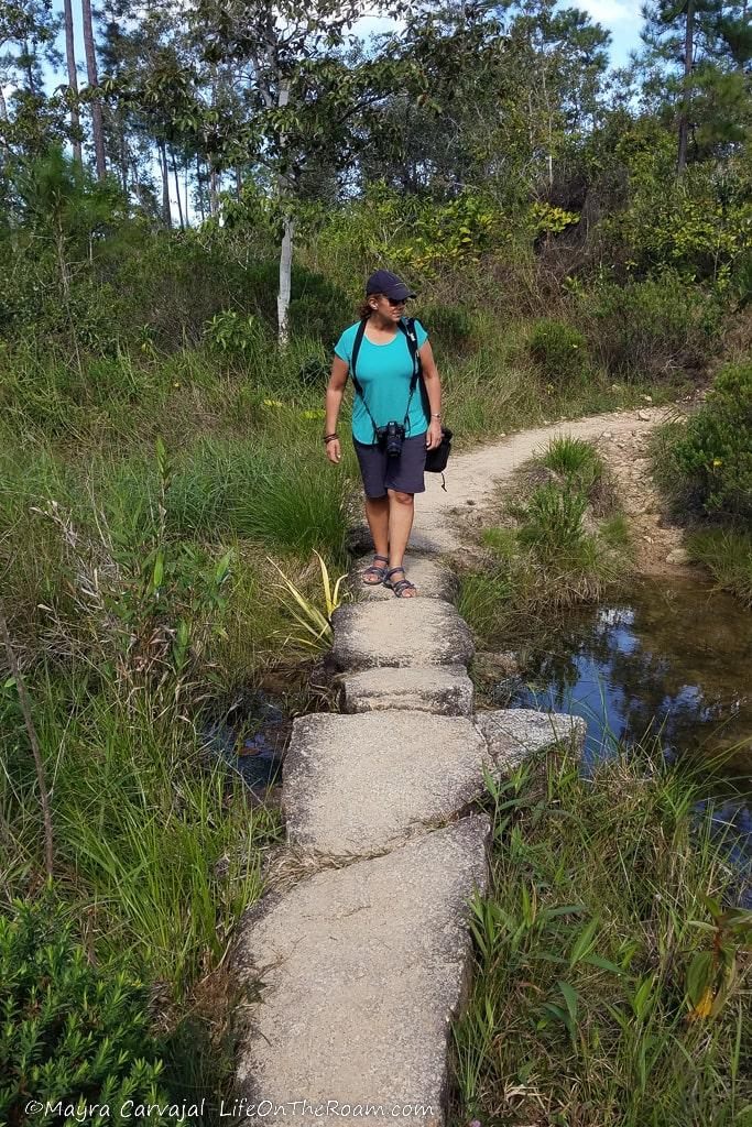 A woman walking on rocks to cross a creek