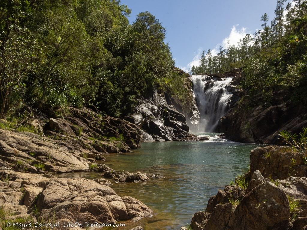 A waterfall in the forest with a pond in the foreground