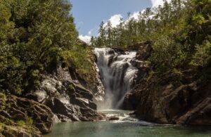 A tall waterfall pouring over rocks in a forest